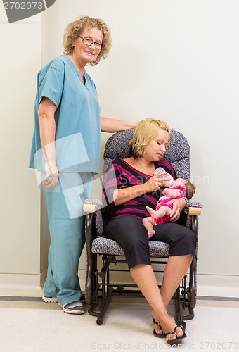 Image of Nurse Standing By Mother Feeding Newborn Babygirl In Hospital