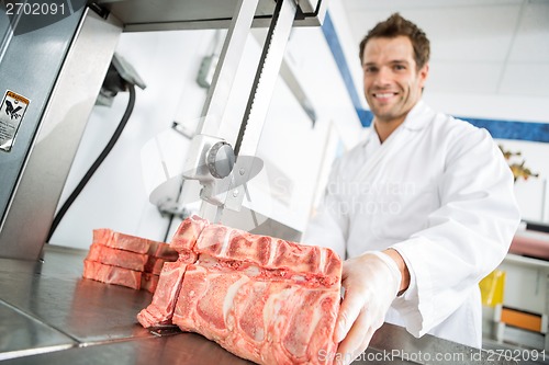 Image of Male Butcher Cutting Meat On Bandsaw