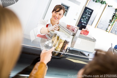 Image of Saleswoman At Counter Attending Customers In Butcher's Shop