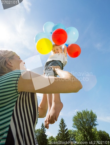 Image of Happy Mother And Daughter Playing With Balloons Against Sky