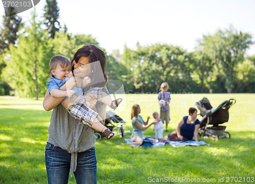 Image of Young Woman Carrying Baby Boy In Park