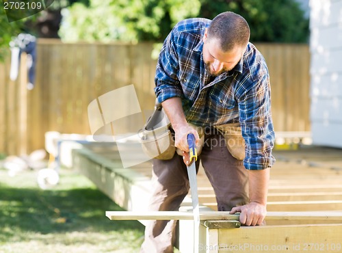 Image of Worker Sawing Wood At Construction Site