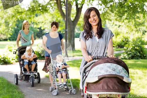 Image of Beautiful Mother Pushing Baby Stroller In Park