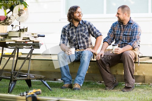 Image of Carpenters Holding Disposable Coffee Cups On Wooden Frame At Sit