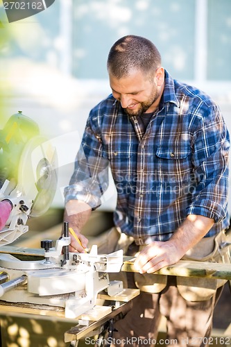 Image of Happy Carpenter Marking On Wood At Table Saw