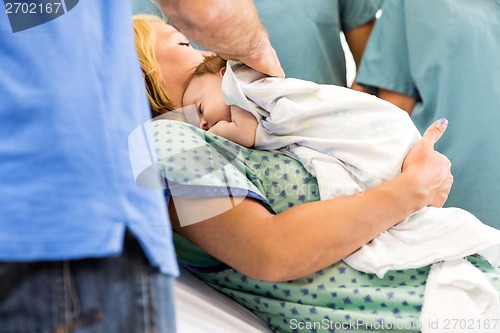 Image of Babygirl Lying On Mother Surrounded By Nurses And Father