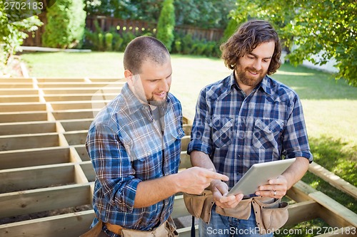 Image of Worker Pointing At Digital Tablet While Discussing Project With