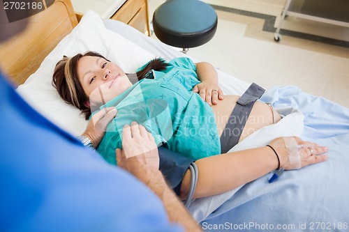 Image of Pregnant Woman Smiling While Being Consoled By Husband In Hospit