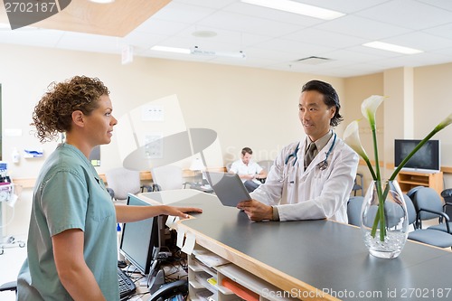 Image of Nurse And Doctor Conversing At Hospital Reception