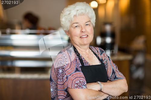 Image of Owner With Arms Crossed Standing In Cafe