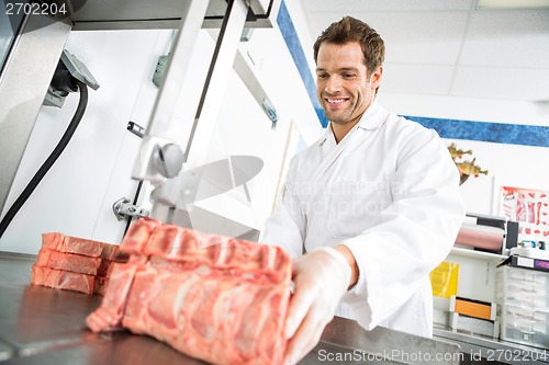 Image of Butcher Cutting Meat On Bandsaw