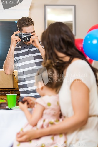 Image of Man Taking Picture Of Family At Birthday Party