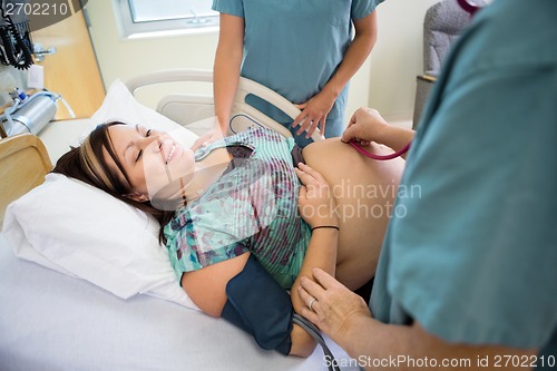 Image of Nurses Examining Smiling Pregnant Woman In Hospital