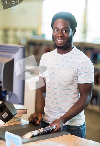 Image of Librarian Scanning Books At Counter In Library