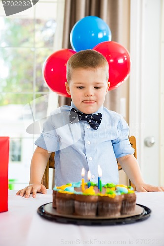 Image of Boy Licking Lips While Looking At Birthday Cake
