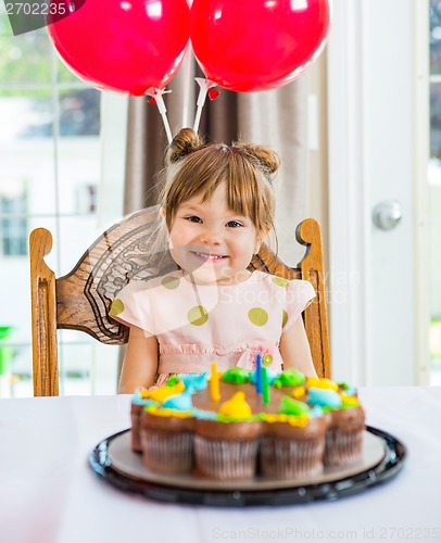 Image of Happy Girl Sitting In Front Of Cake At Home