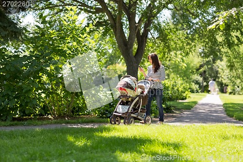 Image of Mother Pushing Baby Carriage In Park