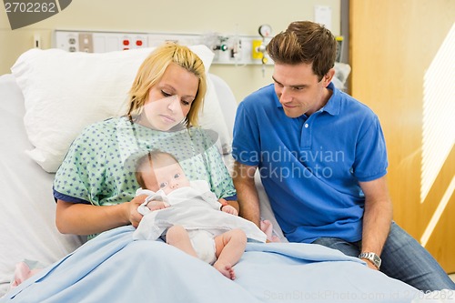 Image of Couple Looking At Newborn Baby In Hospital Room