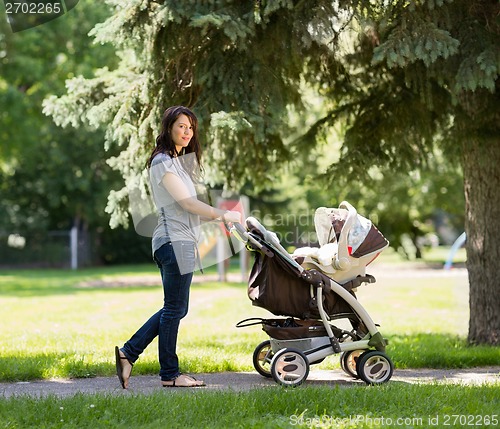 Image of Young Mother Pushing Stroller In Park