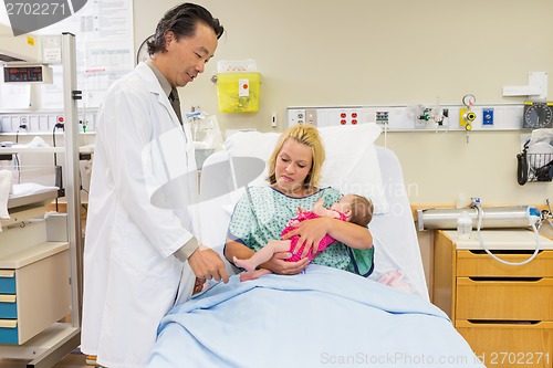 Image of Mother Looking At Doctor Playing With Newborn Babygirl