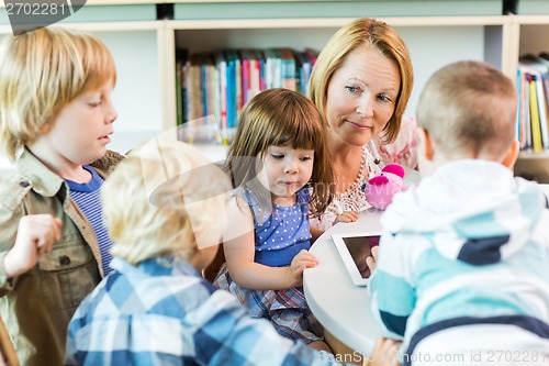 Image of Teacher With Students Using Digital Tablet In Library