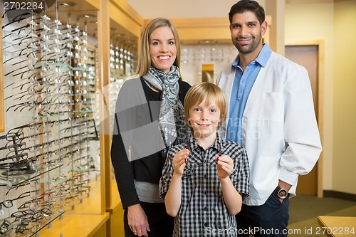 Image of Boy Holding Glasses With Mother And Optician In Store