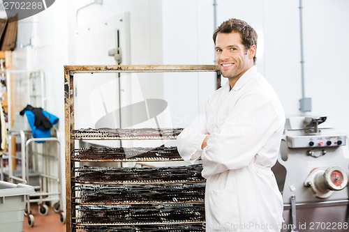Image of Confident Worker Standing By Rack Of Beef Jerky At Shop