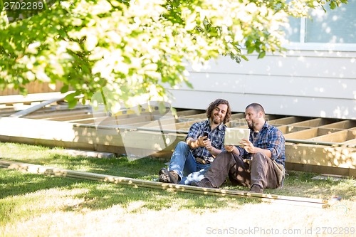 Image of Workers With Mobilephone And Digital Tablet Leaning On Wooden Fr