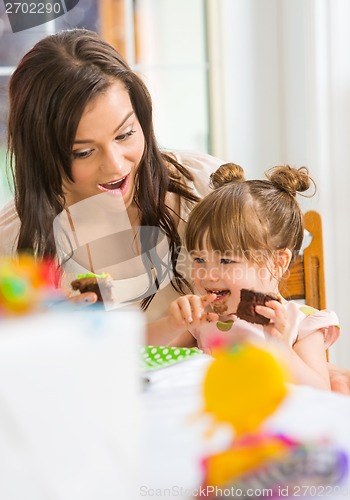 Image of Mother Looking At Girl Eating Cupcake