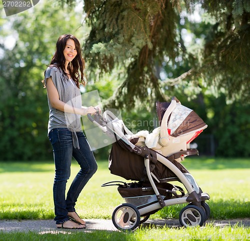 Image of Beautiful Woman Pushing Baby Carriage In Park