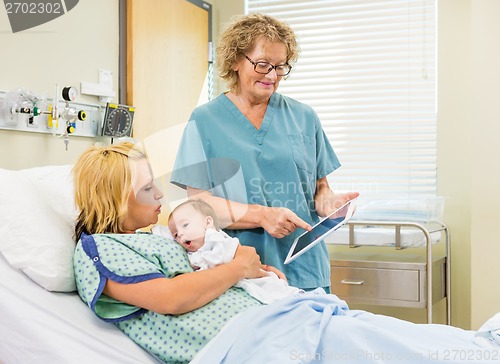 Image of Nurse Explaining Reports On Digital Tablet To Woman With Babygir