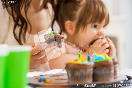 Image of Mother Holding Cupcake With Girl Eating Cake