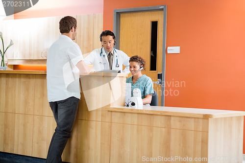 Image of Medical Team Working At Reception While Patient Standing In Hosp