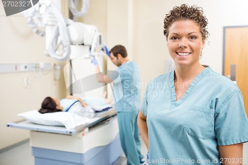 Image of Nurse Smiling While Colleague Preparing Patient For Xray