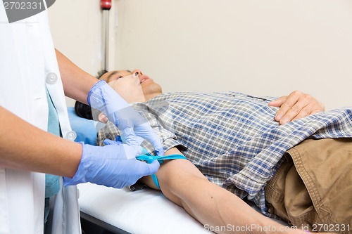 Image of Nurse Tying Strap On Patient's Arm Before Blood Collection