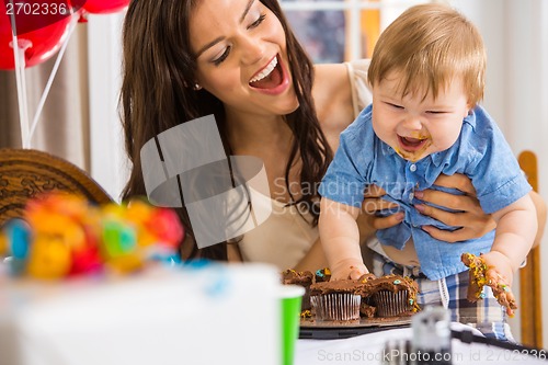 Image of Mother Holding Boy With Messy Hands Covered With Cake Icing
