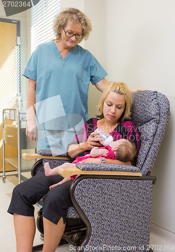 Image of Nurse Looking At Woman Feeding Newborn Babygirl On Chair