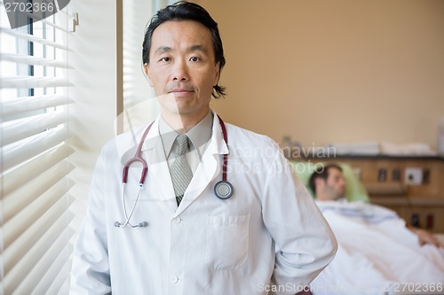 Image of Confident Doctor With Patient In Background At Hospital Room