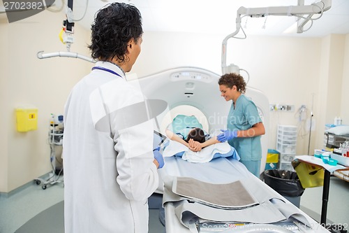 Image of Doctor Looking At Nurse Preparing Patient For CT Scan