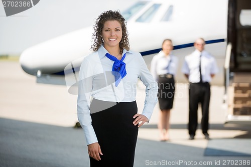 Image of Airhostess With Hand On Hip Standing At Airport Terminal