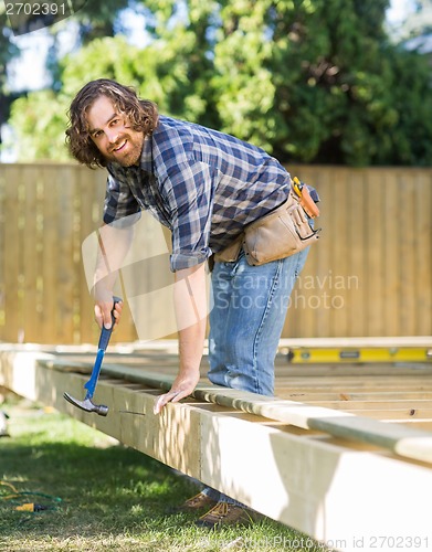 Image of Manual Worker Hammering Nail Into Wood At Site