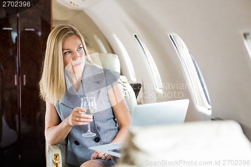 Image of Businesswoman Looking Through Window Of Private Jet