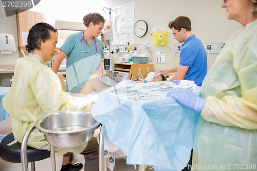 Image of Doctor Operating Pregnant Woman During Delivery With Man And Nur