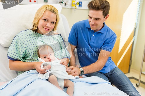 Image of Woman With Newborn Baby Girl Sitting By Man In Hospital