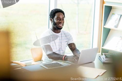 Image of Student Using Laptop While Studying In Library