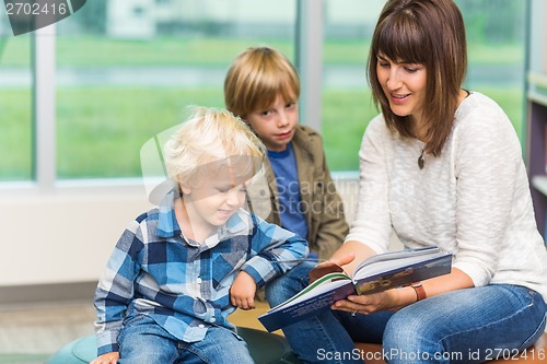 Image of Teacher With Schoolboys Reading Book In Library