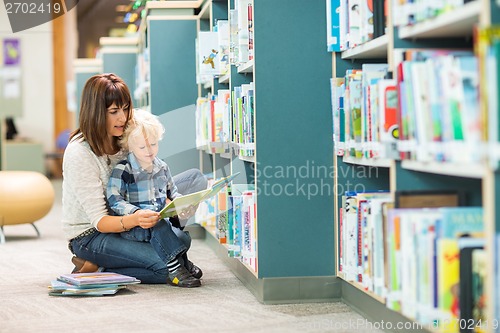 Image of Teacher And Boy Reading Book By Bookshelf