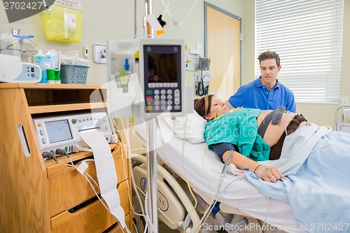 Image of Man Looking At Pregnant Wife Lying On Hospital Bed