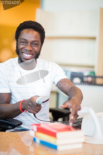 Image of Librarian Scanning Books At Library Desk