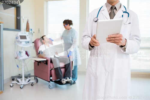 Image of Doctor Holding Digital Tablet In Chemo Room